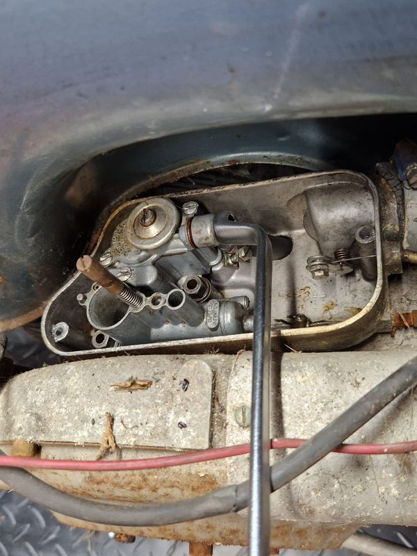 Carburateur en gasbediening onder het plaatwerk van een klassieke Vespa