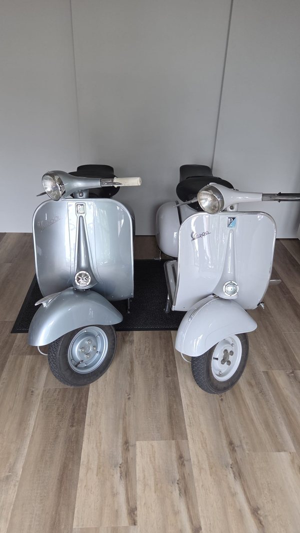 Twee volledig gerestaureerde grijze Vespa's naast elkaar in de garage